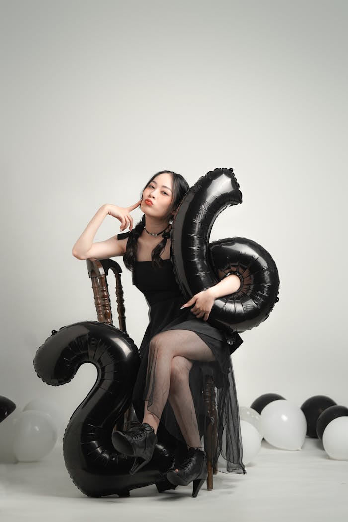 services-02 Elegant woman celebrating her 26th birthday with black balloons in a studio setting.